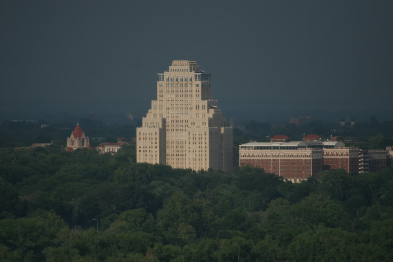 The Chase Park Plaza tower rising above the trees of Forest Park under a storm sky