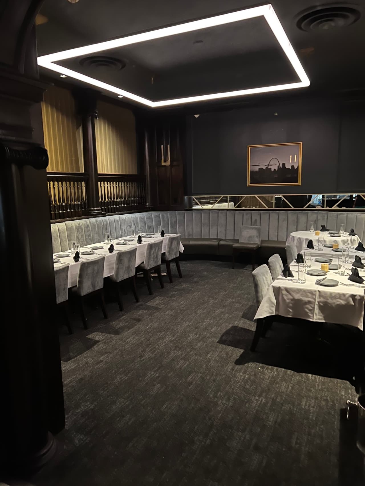 The Middle Room’s curved banquette and set tables beneath a square halo light