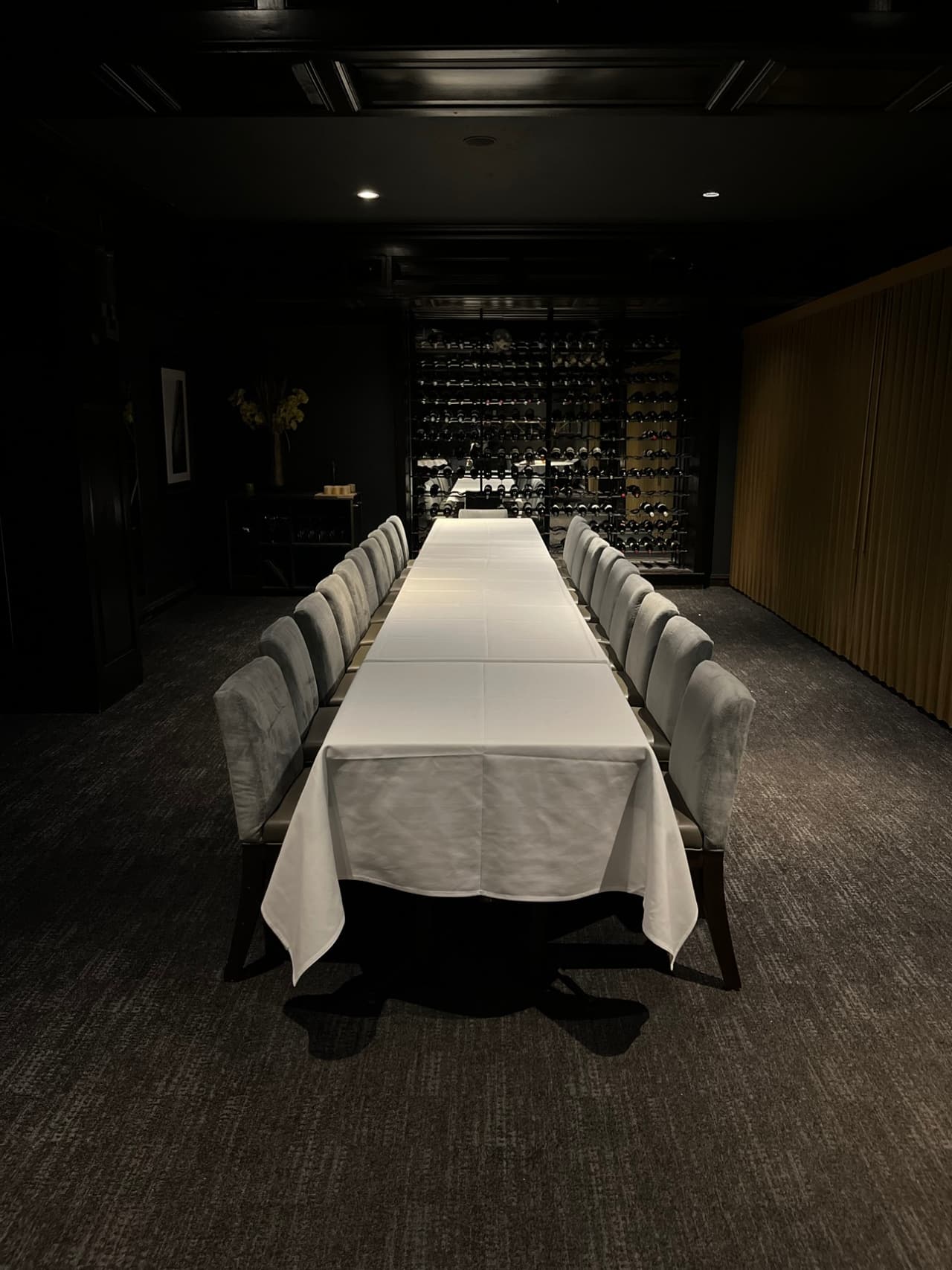 A long banquet table set Upstairs before the wine wall