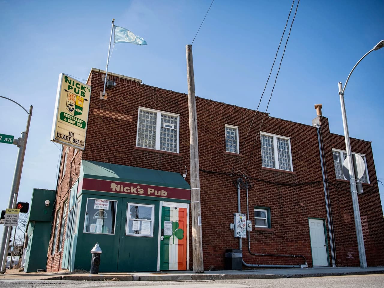 Nick’s Pub on its Dogtown corner, green-trimmed brick under its tall sign