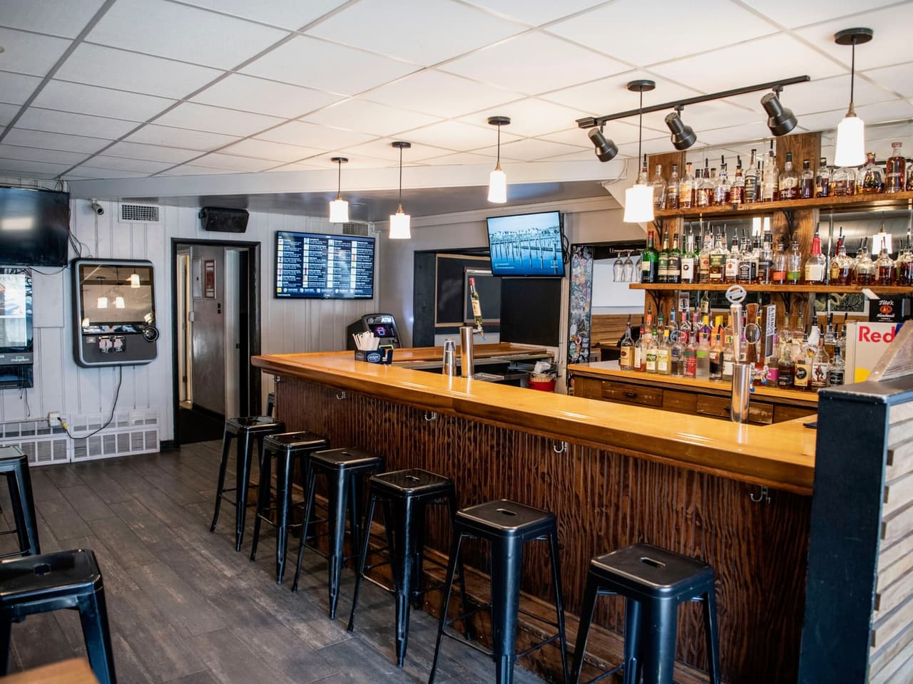 The bar at Tamm Ave, lined with stools under a wall of bottles and TVs